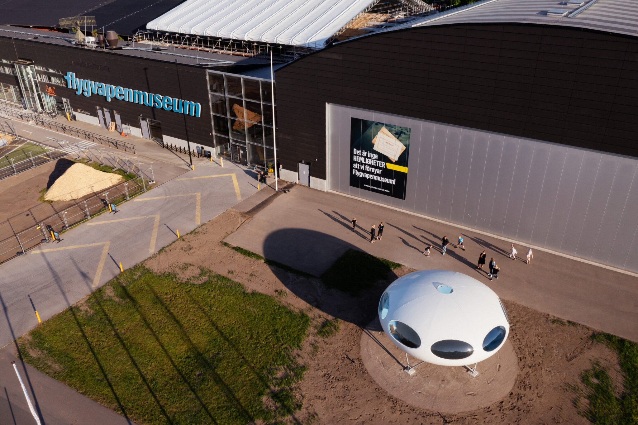 Det ellipsformade vita huset st&aring;r snett till h&ouml;ger om entr&eacute;n till Flygvapenmuseum.