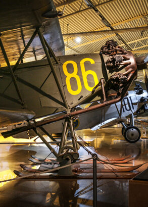 Ett &auml;ldre propellerflygplan med dukkl&auml;dda vingar och siffran 86 i gult p&aring; ena sidan. Bakom skymtas fler flygplan.