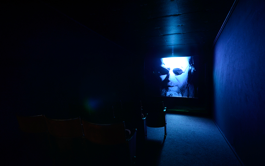 Ett m&ouml;rkt rum med visning av en film, stolar skymtas i m&ouml;rkret.