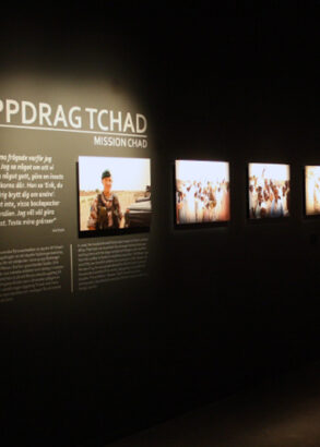 Uppdrag Tchad st&aring;r det p&aring; den svarta v&auml;ggen som &auml;ven pryds av flera fotografier fr&aring;n utst&auml;llningen.