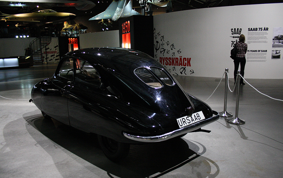 En svart Saab 92001, k&auml;nd under namnet Uursab, st&aring;r i en utst&auml;llningshall. P&aring; en v&auml;gg l&auml;ngre bort st&aring;r det Saab 75 &aring;r.