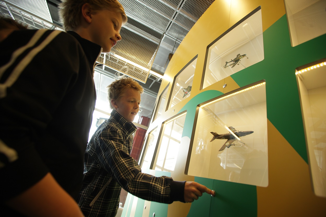 Tv&aring; barn trycker p&aring; knappar och lyssnar till de olika flygplanens olika ljud.