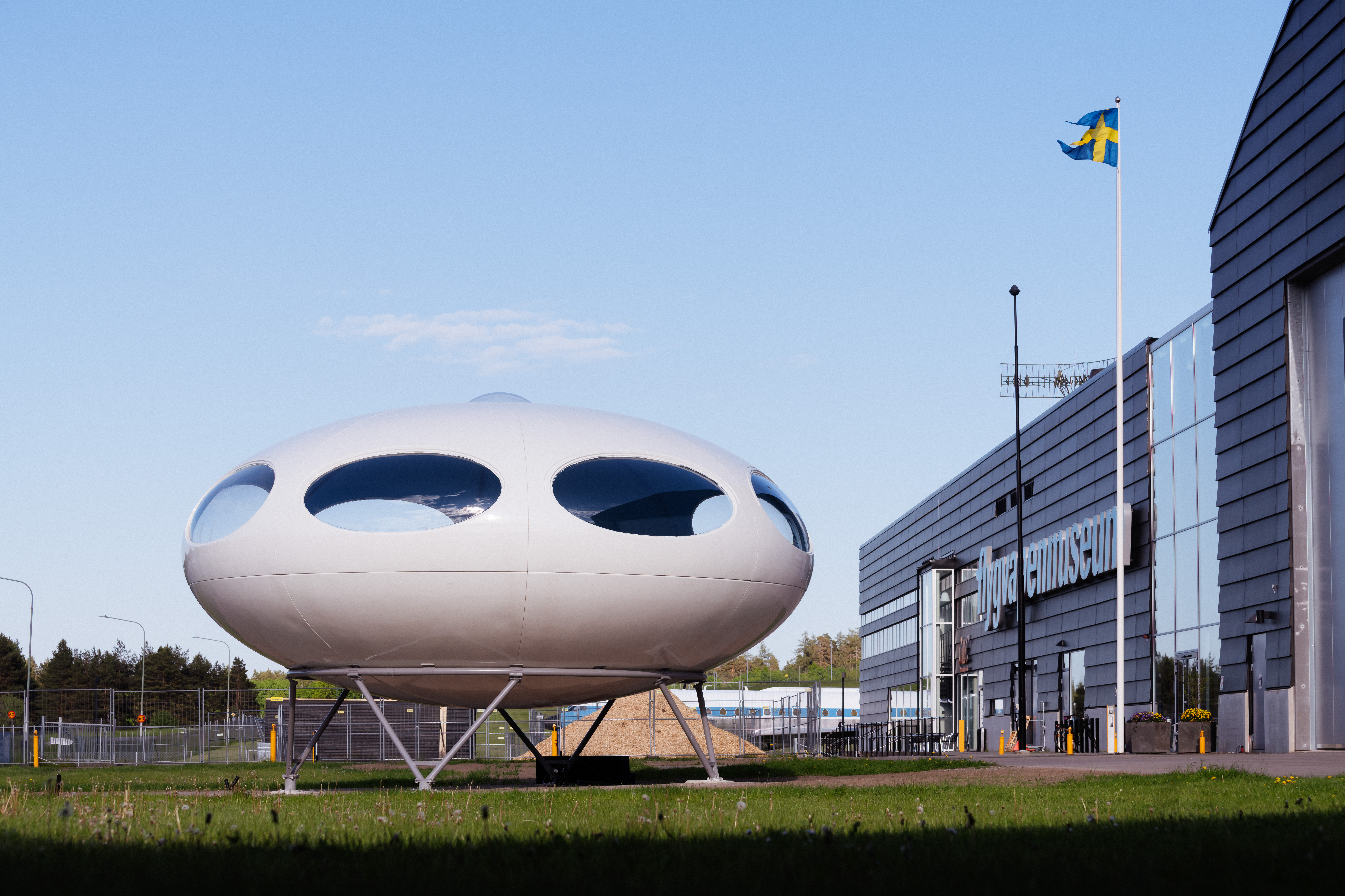 Det ellipsformade vita huset st&aring;r snett till h&ouml;ger om entr&eacute;n till Flygvapenmuseum.