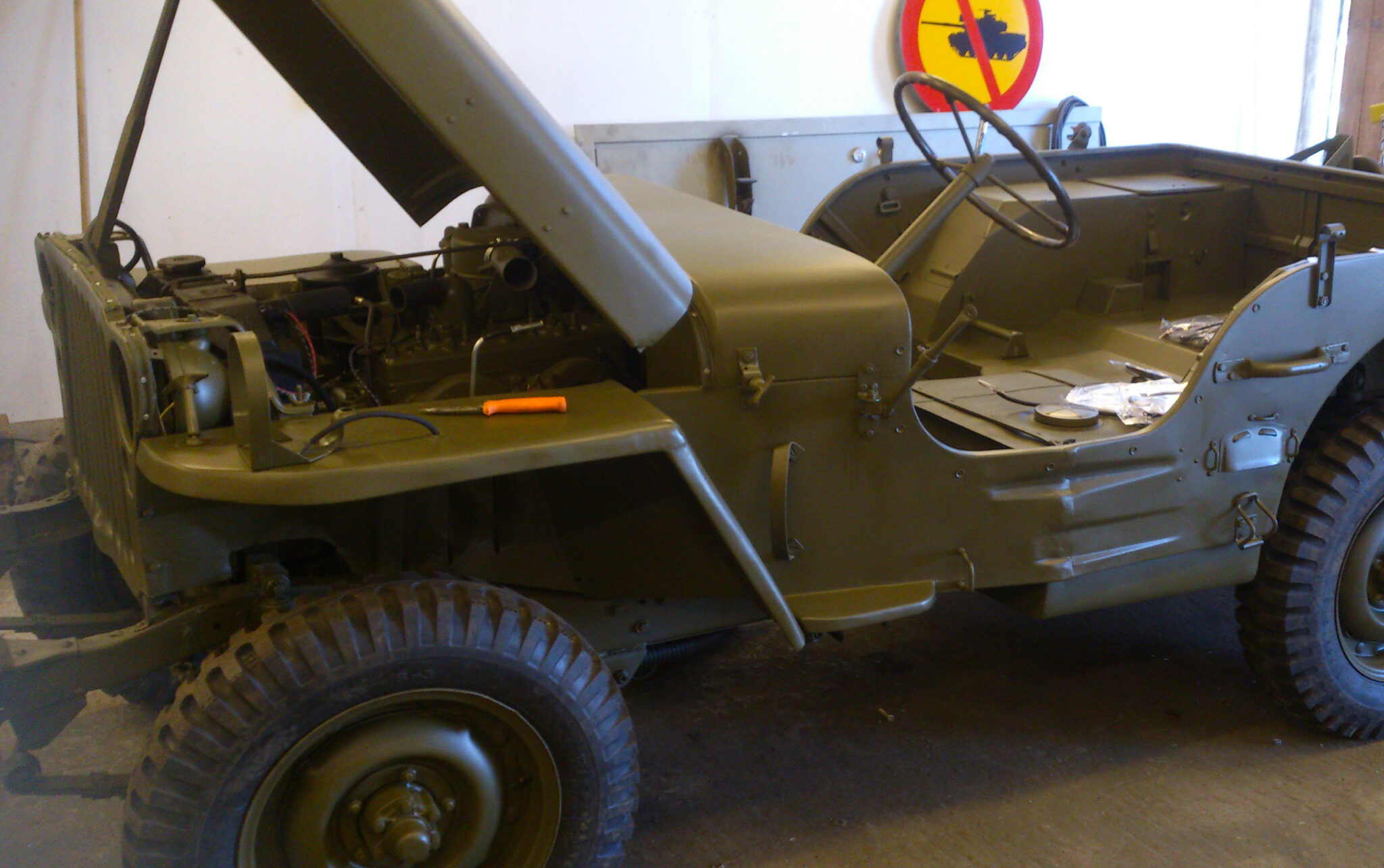 En gr&ouml;n jeep utan tak med motorhuven fullt &ouml;ppnad.