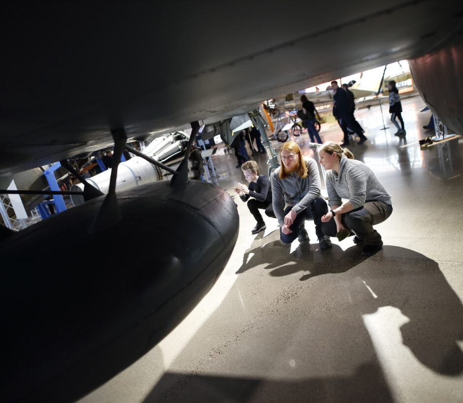 N&aring;gra bes&ouml;kare sitter p&aring; huk f&ouml;r att kolla under ett flygplan.