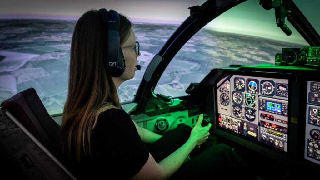 En besökare testar får Saab 105 / SK 60-simulator. Den stora skärmen ger henne känslan av att vara upp bland molnen