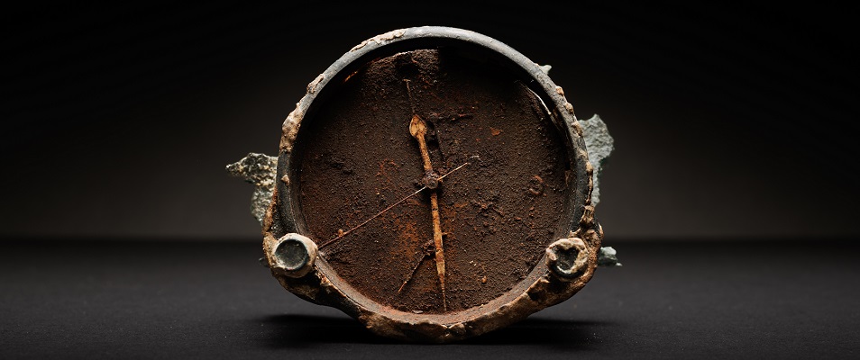 En rostig klocka där visarna har stannat på halv tolv. Hittad i samband av bärgningen av DC3:an.