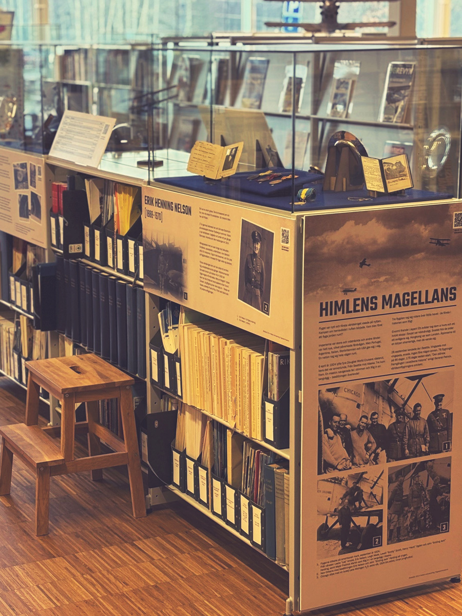 En glasmonter med souvenirer st&aring;r p&aring; en bokhylla med fulla dokumenth&aring;llare.