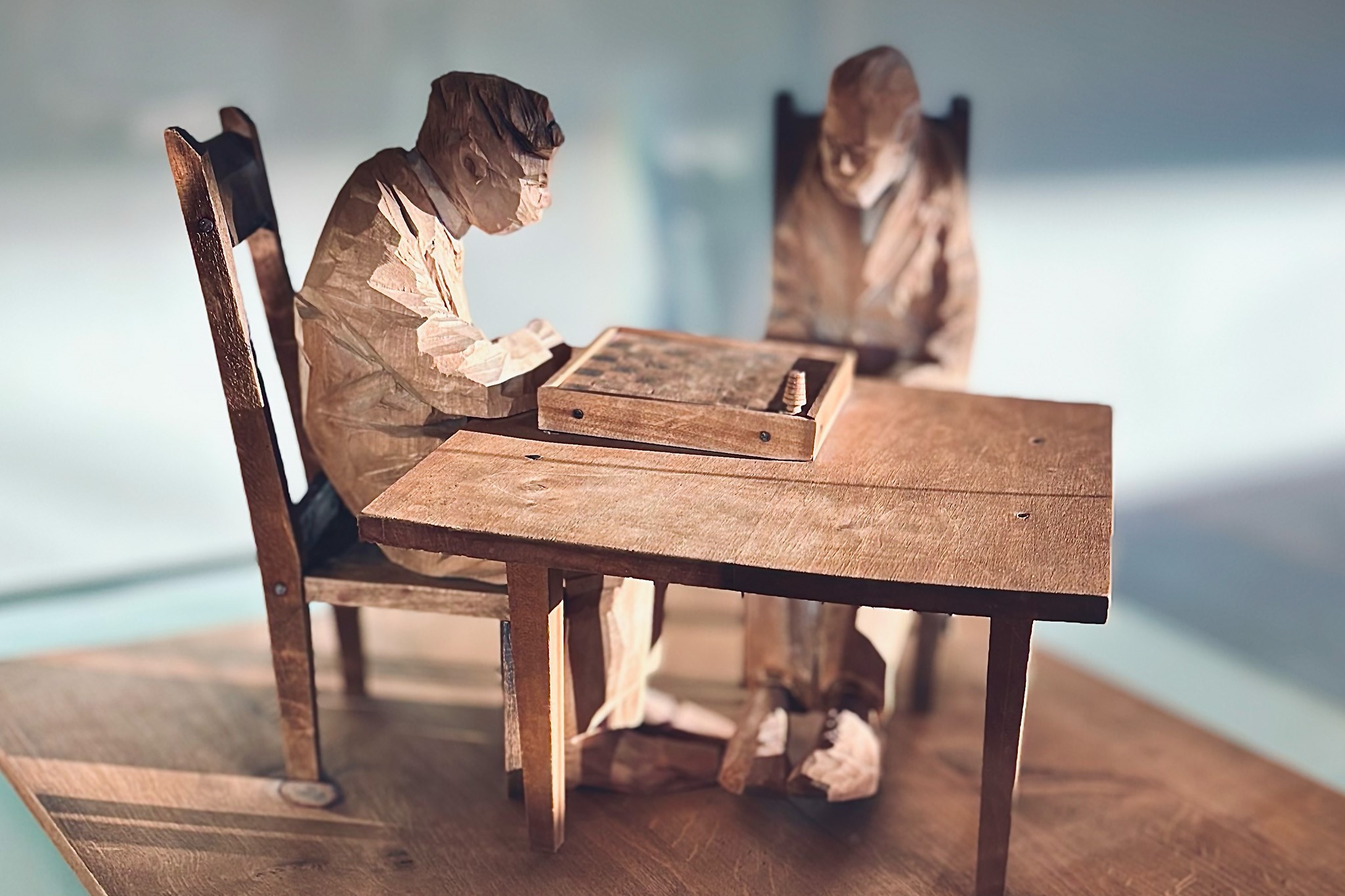 Tv&aring; t&auml;ljda tr&auml;gubbar sittandes p&aring; varsin stol vid ett bord med ett br&auml;dspel framf&ouml;r sig